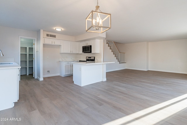 kitchen with a kitchen island, stainless steel range with electric stovetop, decorative light fixtures, white cabinetry, and light hardwood / wood-style floors