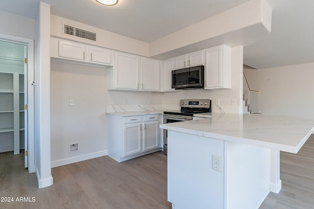 kitchen with light hardwood / wood-style floors, white cabinetry, light stone counters, kitchen peninsula, and stainless steel appliances