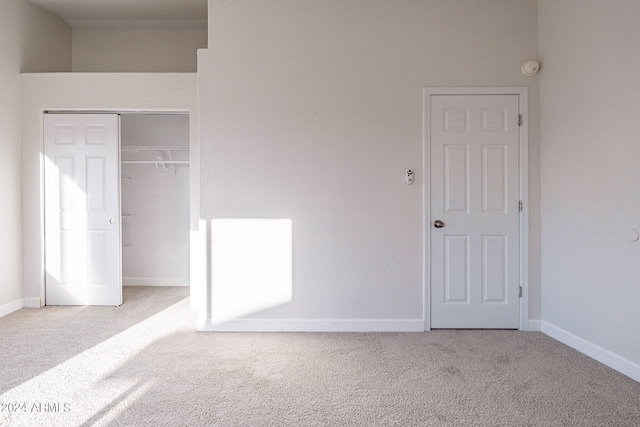 unfurnished bedroom featuring light colored carpet and a closet