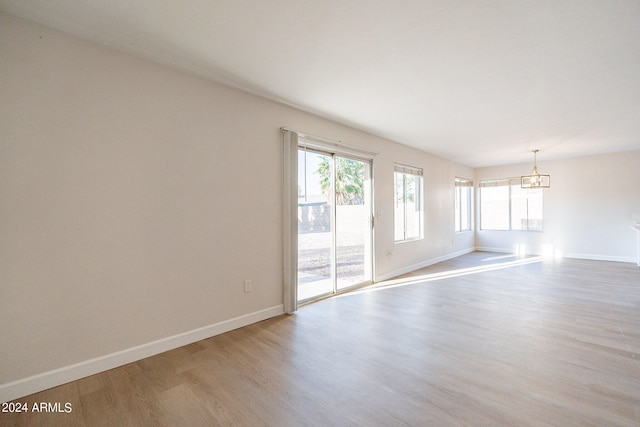 empty room featuring a chandelier and hardwood / wood-style floors