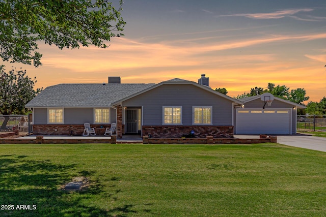 view of front of property featuring brick siding, a lawn, a chimney, and concrete driveway