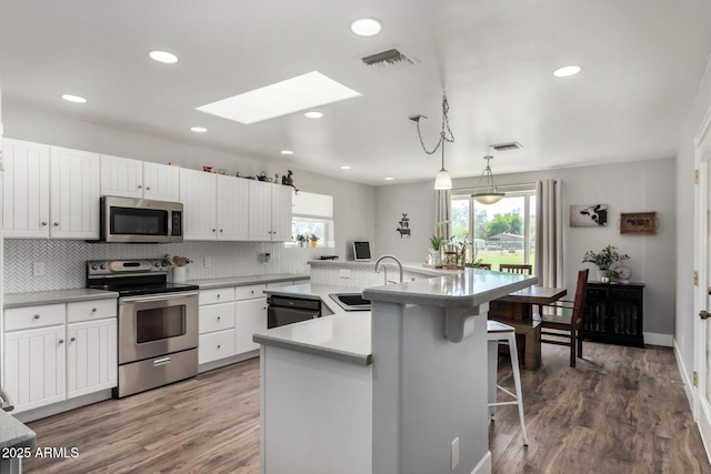kitchen featuring a sink, a skylight, decorative backsplash, appliances with stainless steel finishes, and visible vents