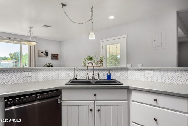 kitchen featuring backsplash, light countertops, stainless steel dishwasher, and a sink