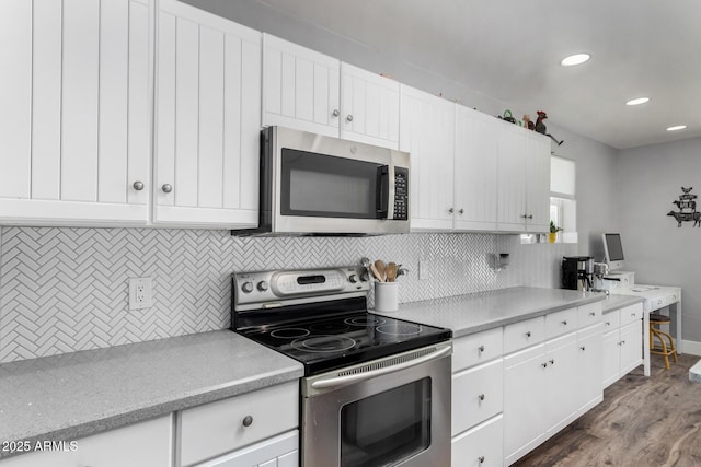 kitchen with backsplash, dark wood-type flooring, baseboards, appliances with stainless steel finishes, and white cabinetry