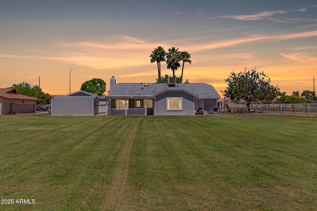 back of property at dusk with fence, a sunroom, and a yard
