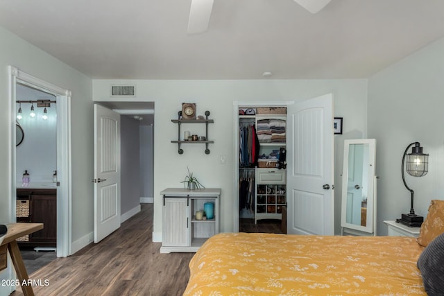 bedroom featuring baseboards, visible vents, wood finished floors, a closet, and a walk in closet