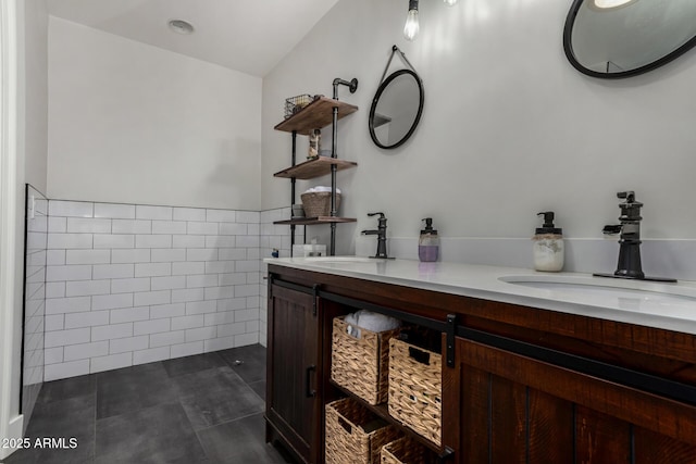 bathroom with tile patterned flooring, a sink, double vanity, and tile walls