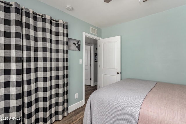 bedroom with wood finished floors, visible vents, and baseboards