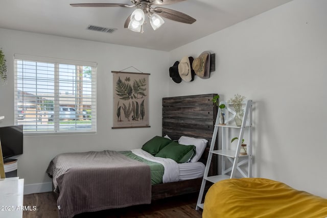 bedroom featuring baseboards, wood finished floors, visible vents, and ceiling fan