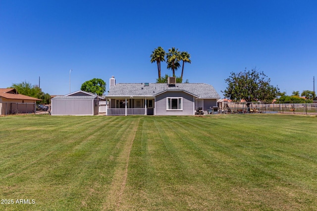 back of property with a yard, a sunroom, a chimney, and fence
