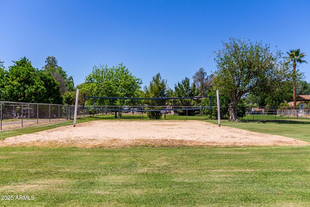 surrounding community with volleyball court, fence, and a lawn