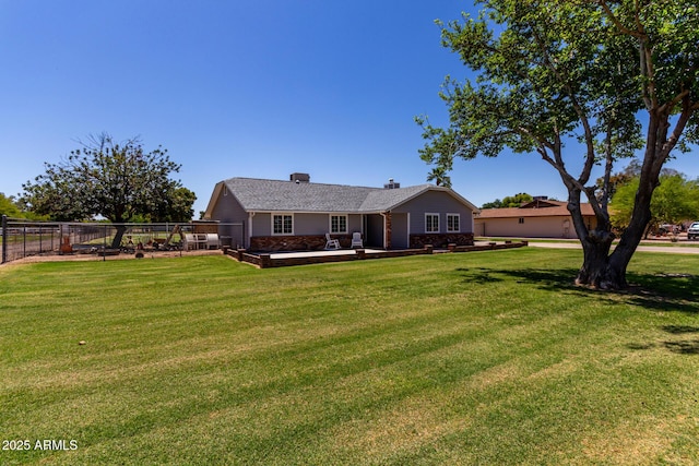 rear view of house with a yard, a chimney, and fence