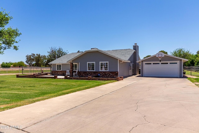 view of front facade featuring fence, a front lawn, an outdoor structure, a detached garage, and brick siding