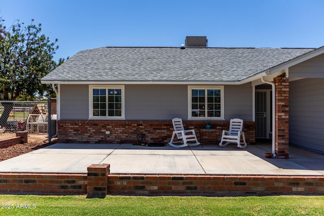 back of property featuring fence, a patio area, a shingled roof, and brick siding