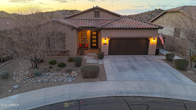 view of front of house featuring a garage, a tiled roof, concrete driveway, and stucco siding