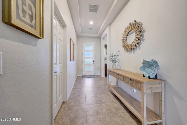 doorway with light tile patterned floors, baseboards, and visible vents