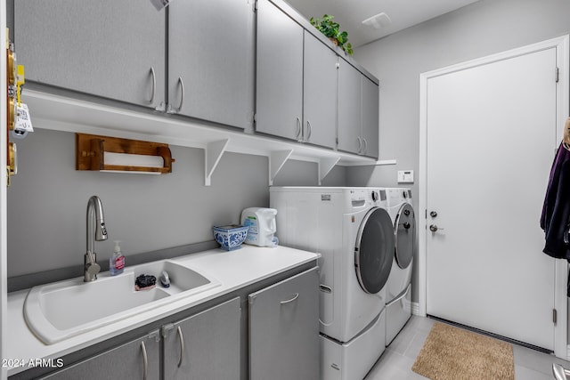 clothes washing area featuring washer and clothes dryer, light tile patterned flooring, cabinets, and sink