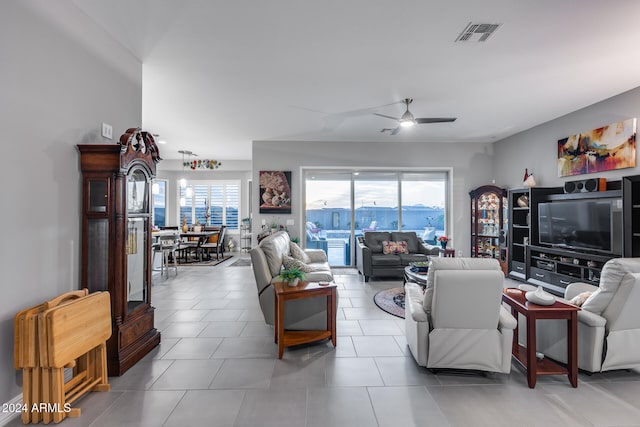 living room with a wealth of natural light, ceiling fan, and light tile patterned flooring