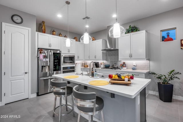 kitchen featuring pendant lighting, white cabinetry, a kitchen island with sink, and appliances with stainless steel finishes