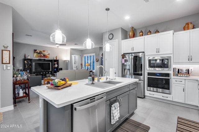 kitchen with appliances with stainless steel finishes, decorative light fixtures, white cabinetry, and a center island with sink