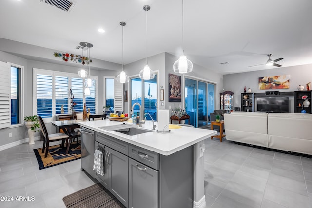 kitchen featuring gray cabinetry, hanging light fixtures, stainless steel dishwasher, ceiling fan, and an island with sink