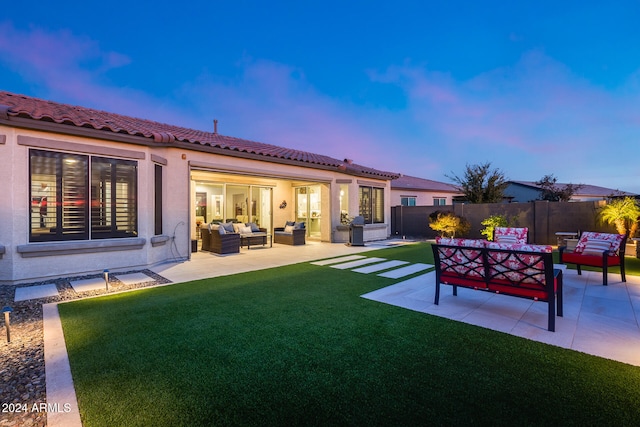 back house at dusk with outdoor lounge area, a yard, and a patio