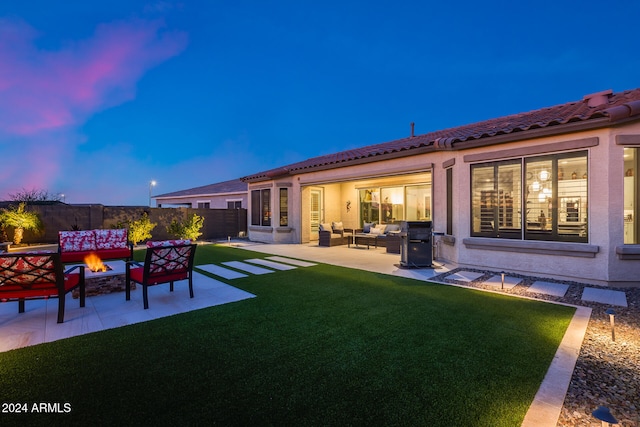 back house at dusk featuring a lawn, an outdoor living space with a fire pit, and a patio