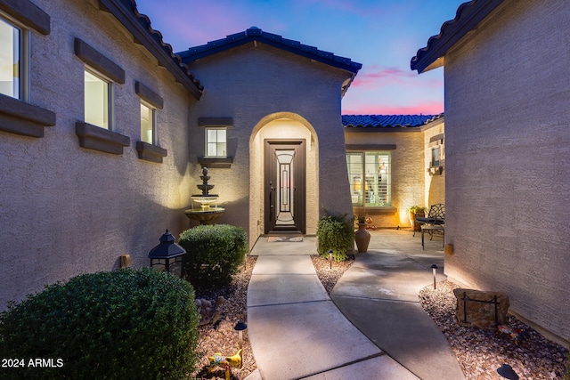 exterior entry at dusk featuring a patio area