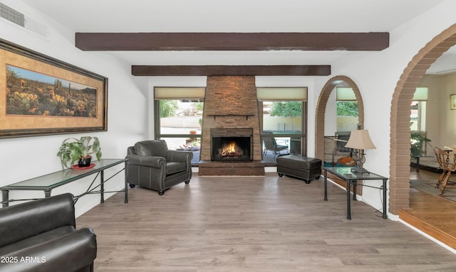 1298 E Buffalo St, Chandler, AZ 85225 - living area featuring beamed ceiling, arched walkways, light wood-style floors, a fireplace, and baseboards
