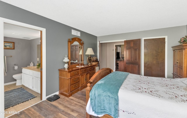 1298 E Buffalo St, Chandler, AZ 85225 - bedroom with light wood-style flooring, connected bathroom, and baseboards