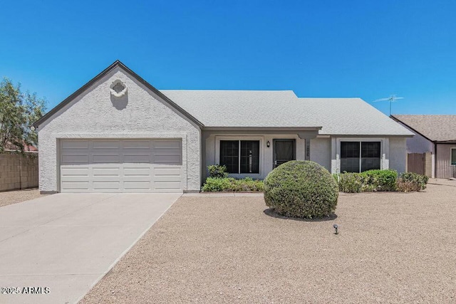 ranch-style house featuring driveway, a garage, fence, and stucco siding