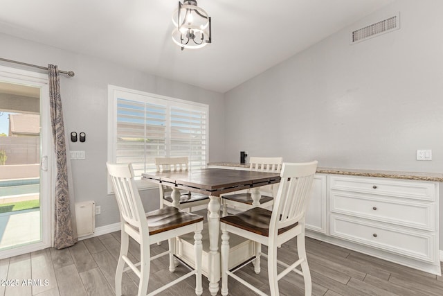 dining room featuring a notable chandelier, visible vents, baseboards, and light wood finished floors