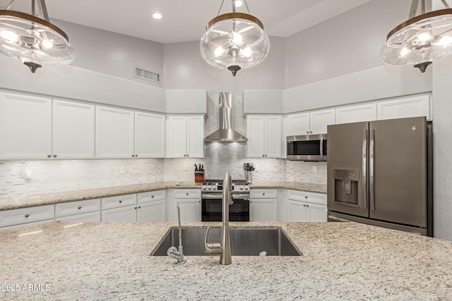 kitchen featuring a chandelier, stainless steel appliances, wall chimney exhaust hood, and visible vents