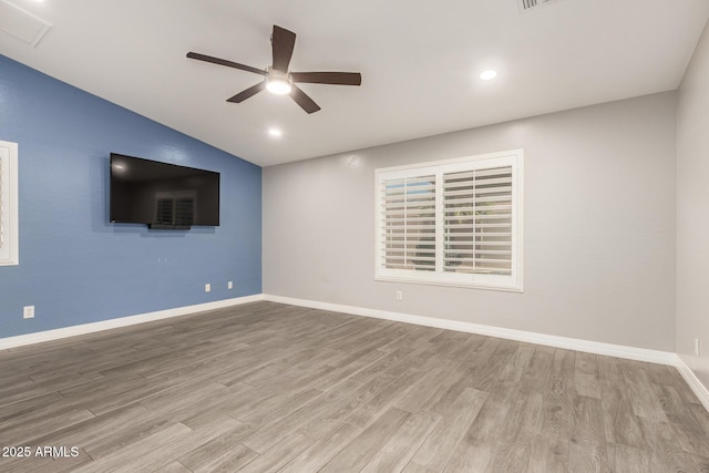 unfurnished room with a ceiling fan, visible vents, vaulted ceiling, wood finished floors, and baseboards