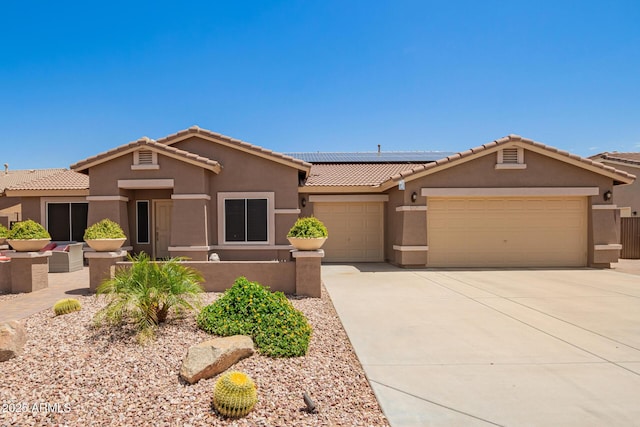view of front of home featuring an attached garage, stucco siding, roof mounted solar panels, a tiled roof, and driveway
