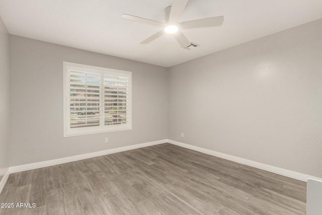 spare room featuring baseboards, ceiling fan, visible vents, and wood finished floors