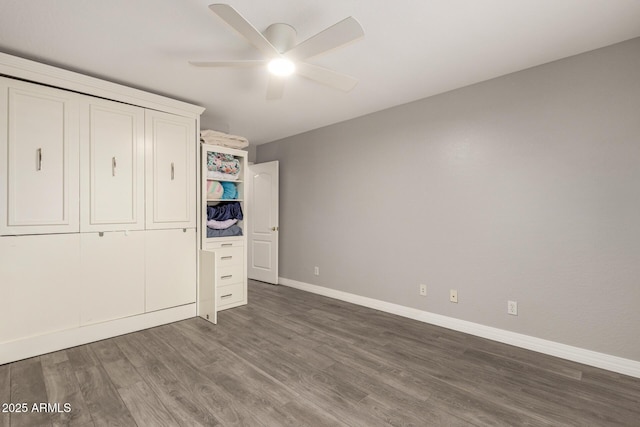 unfurnished bedroom featuring baseboards, a ceiling fan, and dark wood-style floors