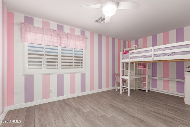 unfurnished bedroom with ceiling fan, wood finished floors, and wallpapered walls