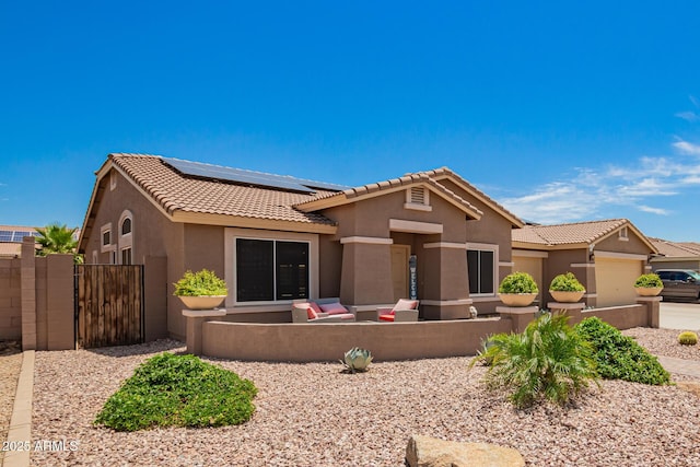 view of front of house featuring fence, a tile roof, a garage, stucco siding, and roof mounted solar panels