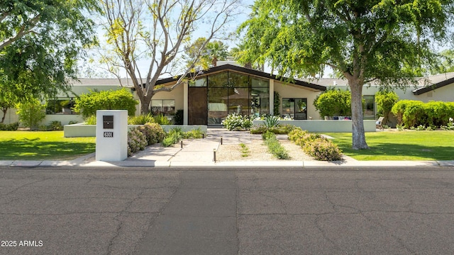 mid-century home featuring a front lawn