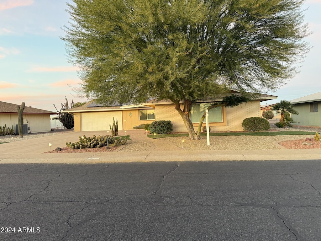 view of front of home featuring central AC unit, solar panels, and a garage