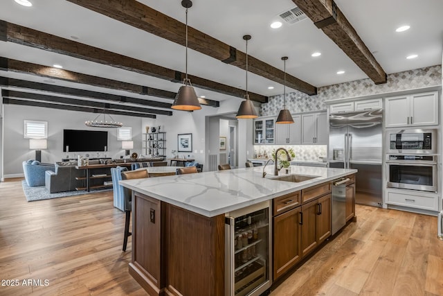 kitchen featuring sink, white cabinets, wine cooler, a kitchen island with sink, and built in appliances