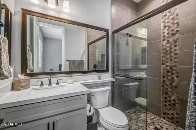 bathroom with vanity, a shower with shower door, and toilet