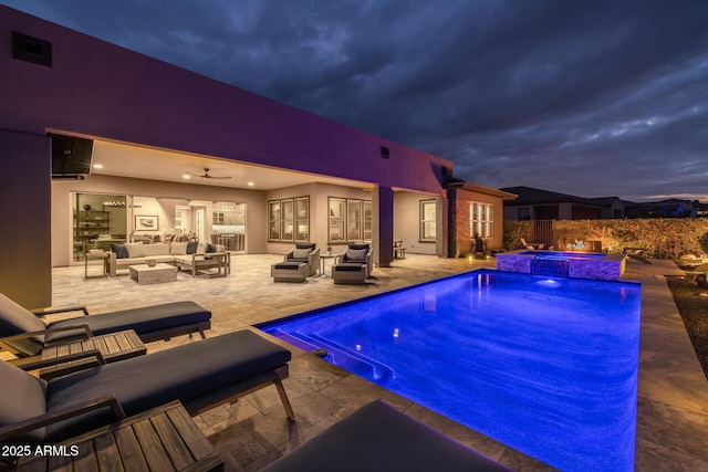 pool at dusk featuring an outdoor living space, a patio area, ceiling fan, and an in ground hot tub