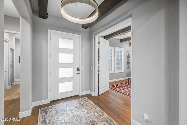 entrance foyer featuring wood-type flooring and beamed ceiling