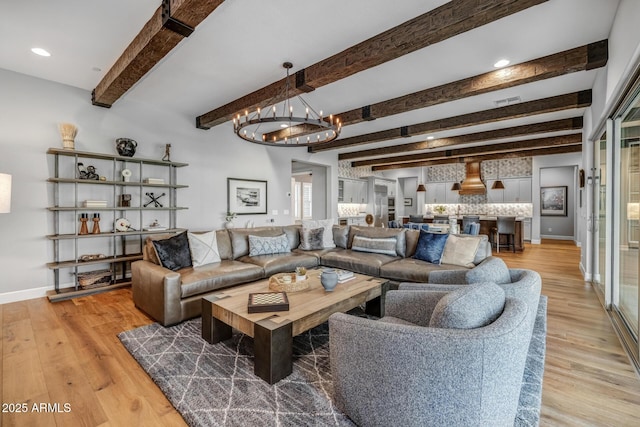 living room with beamed ceiling, an inviting chandelier, and light hardwood / wood-style floors