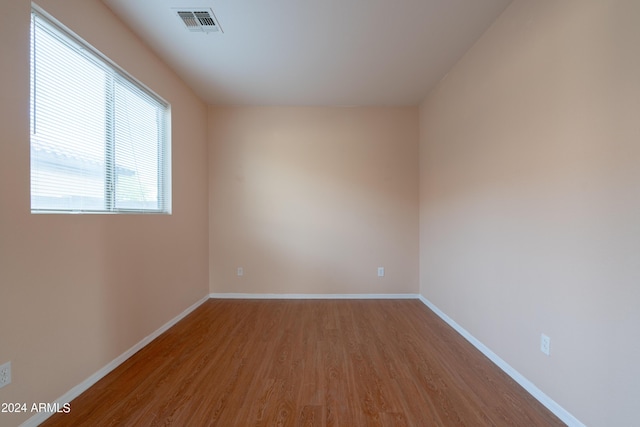 unfurnished room featuring baseboards, wood finished floors, and visible vents