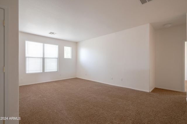 carpeted empty room with visible vents and baseboards