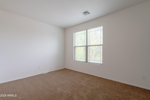 carpeted spare room featuring baseboards and visible vents