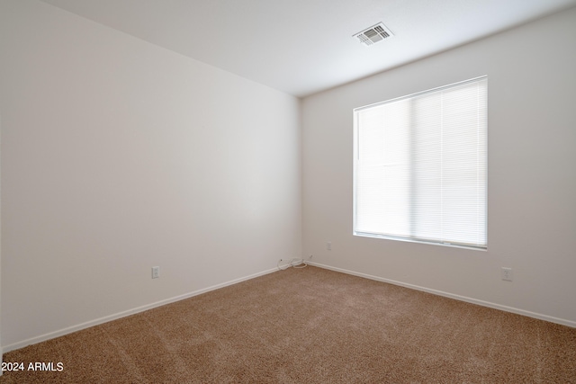 spare room with carpet floors, baseboards, and visible vents